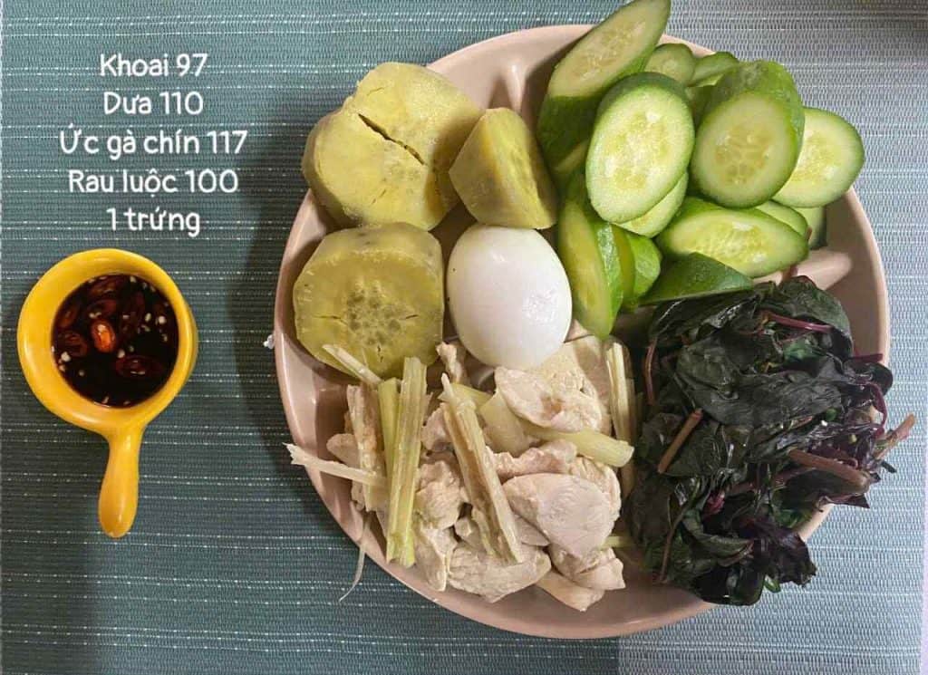 Thức ăn giảm cân gồm dưa chuột, khoai môn, trứng, gà chín, rau luộc, nấm, nước sốt ớt trong chén nhỏ.